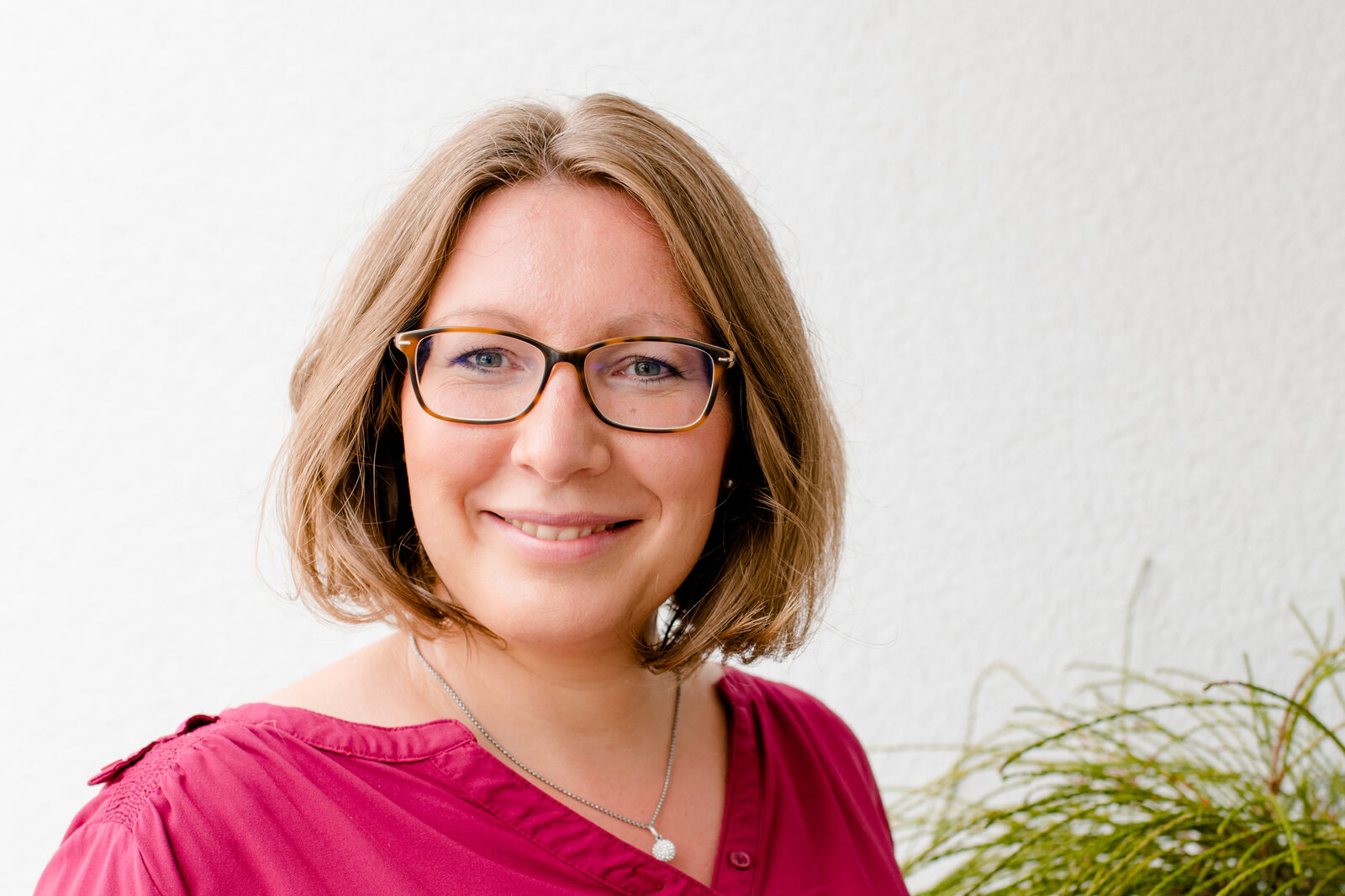 Kerstin Hiemer lächelt freundlich vor heller Wand, bereit für ein Gespräch