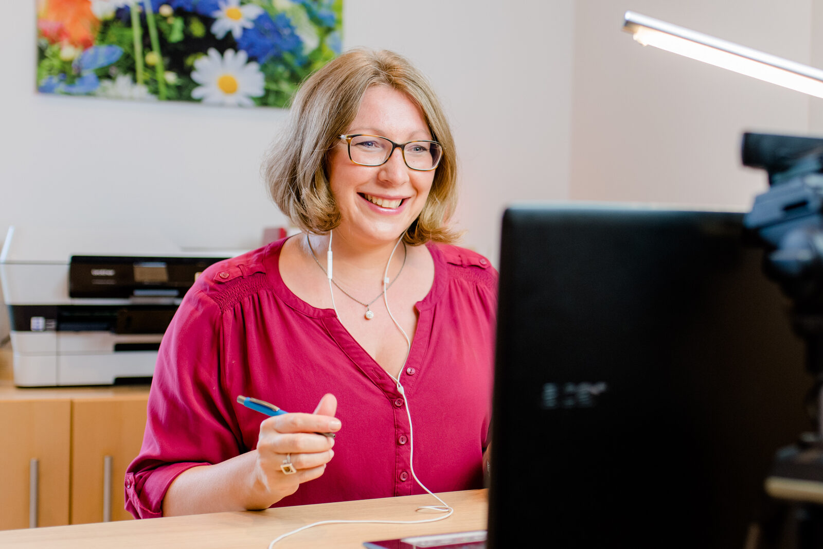 Kerstin Hiemer lächelt während einer Videoaufnahme an ihrem Schreibtisch
